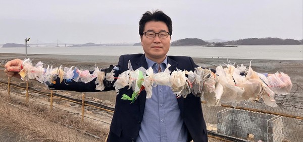 장정구 인천녹색연합 전 정책위원장이 해양쓰레기의 문제점을 알리기 위해 강화대교 아래 해양쓰레기를 건져 줄에 뀄다. 사진=페이스북